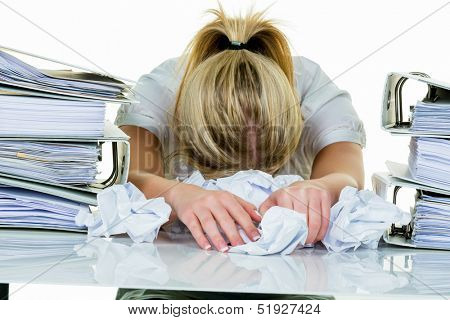 a young woman desperately in office between many file folders and crumpled papier.symbolfoto for stress, burnout and overwork.