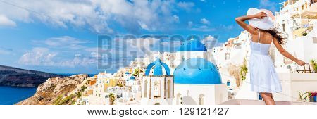 Europe tourist travel woman panorama banner from Oia, Santorini, Greece. Happy young woman looking at famous blue dome church landmark destination. Beautiful girl visiting the Greek islands.