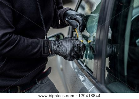 Car Thief Trying To Break Into A Car With A Screwdriver.