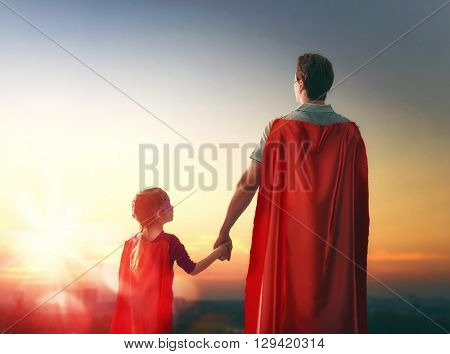 Happy loving family. Father and his daughter child girl playing outdoors. Daddy and his child girl in an Superhero's costumes. Concept of Father's day.