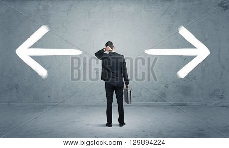 A businessman in doubt, having to shoose between two different choices indicated by arrows pointing in opposite direction concept