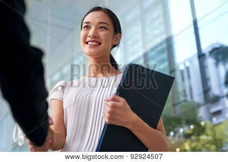 beautiful asian chinese business woman shaking hands in modern city work office