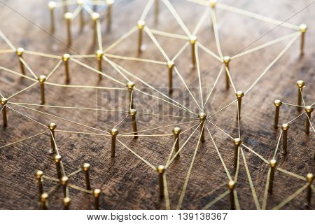 Linking entities. Network, networking, social media, internet communication abstract. Many small network connected to a larger network. Web of gold wires on rustic wood. . Shallow Depth of field.