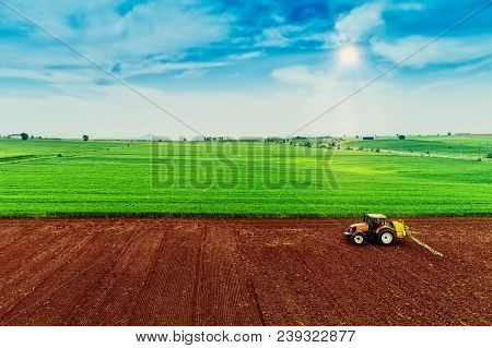 Aerial Shot Of  Farmer With A Tractor On The Agricultural Field Sowing.