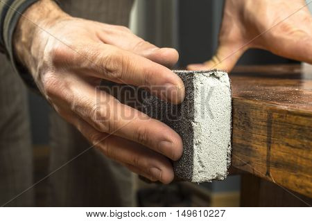 Handyman working with sandpaper on a wooden table