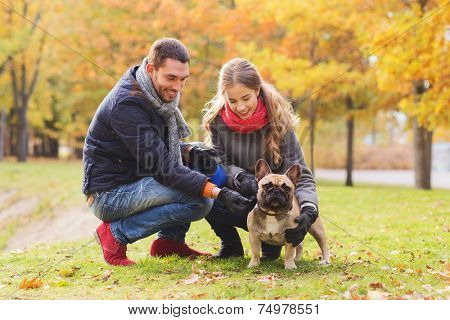 care, animals, family, season and people concept - smiling couple with dog in autumn park