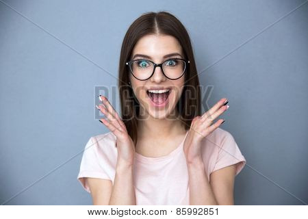 Surprised young woman in glasses over gray background