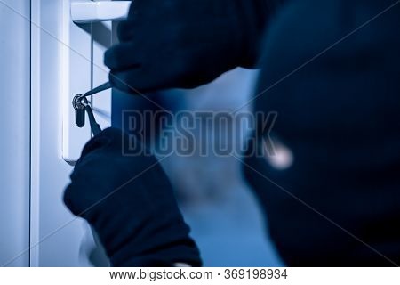 Closeup Of Robber In Black Mask Cracking Door Lock With Metal Picklock Tool During House Breaking