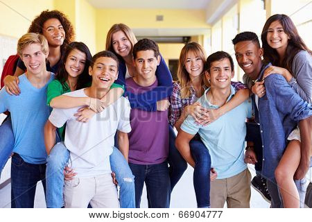 Group Of High School Students Giving Piggybacks In Corridor