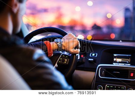 Driving a car at night -man driving his modern car at night in a city (shallow DOF; color toned image)