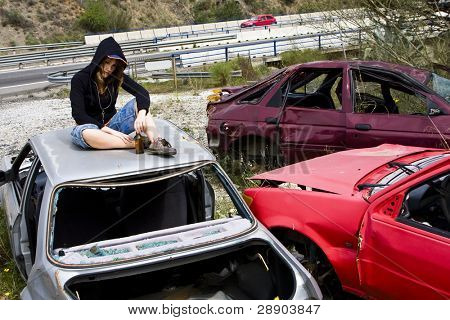 Young woman taking beer in the scrapyard