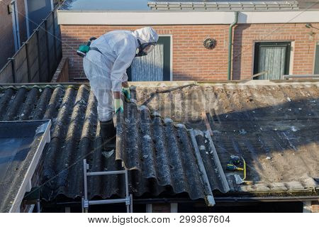 Professional Asbestos Removal. Men In Protective Suits Are Removing Asbestos Cement Corrugated Roofi