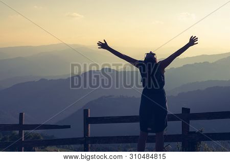 Woman on vacation relaxing in mountain. Summer vacation. Young woman traveler in vacation in nature. Traveler in vacation with backpack in nature. Girl traveler with hands outstretched in vacation. Traveler. Vacation . Backpack. Woman. Nature. Healthy lif