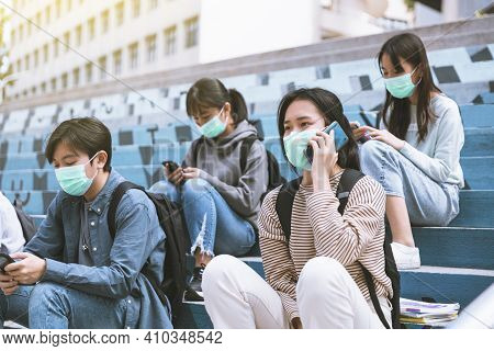 Young Students Wearing With Face Masks And Watching  The Mobile Phone On The Stairs