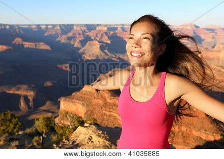 Happy freedom woman tourist in Grand Canyon smiling free in happiness during summer travel trip in Grand Canyon, South Rim, Arizona, USA.