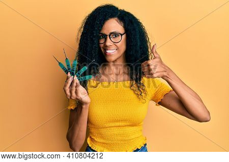 Middle age african american woman holding picklock to unlock security door smiling happy and positive, thumb up doing excellent and approval sign 