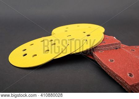 Sandpaper For Sanding Wood, On A Black Background. A Stack Of Yellow Round Sandpaper. Copy Space