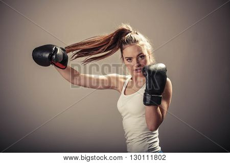 Energy fighting boxing with opponent. Sports and bodybuilding. Strong young woman punch enemy. Girl with ponytail wear white tank top and boxing gloves.