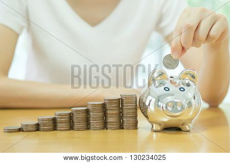 saving money-young woman putting a coin into a money-box-close up