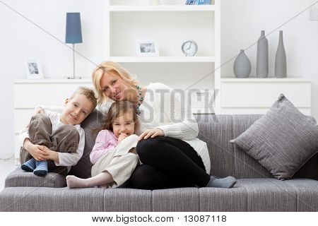 Mãe e filhos sentados juntos no sofá na sala.