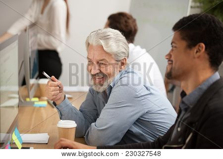 Smiling Senior Employee Discussing Email With African Colleague At Workplace, Happy Older Worker Tal