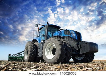 The tractor wheels on the huge field, a farmer riding a tractor, a tractor working in a field agricultural machinery in the work, tractor in the background cloudy sky