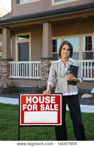 Female Realtor standing by FOR SALE sign