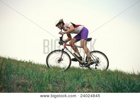 Cyclist riding on a green meadow