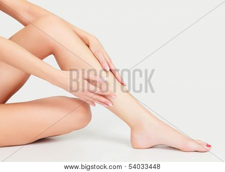 Woman sits on the floor and touches leg by hands 