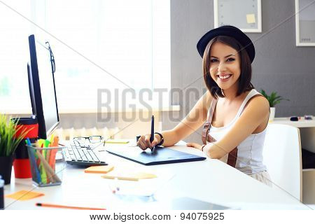 Young Female Designer Using Graphics Tablet While Working With Computer