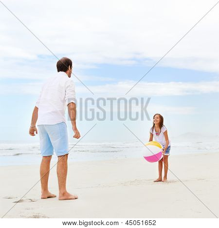 Isä ja tytär, leikkivät rannalla yhdessä hauskaa beachball