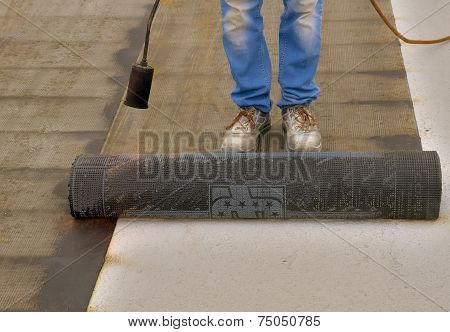 Worker preparing part of bitumen roofing felt