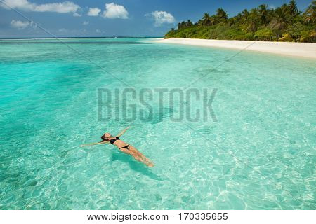 Woman swim and relax in the sea. Happy island lifestyle. White sand, crystal-blue sea of tropical beach. Vacation at Paradise. Ocean beach relax, travel to Maldives islands