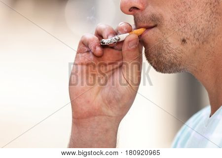 Smoking problem addiction to nicotine concept. Adult man in light shirt smoking cigarette outside.