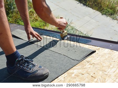 Roofer Contractor Gluing Waterproof Membrane On Wooden Roof Top Surface With Brush And Black Bitumen