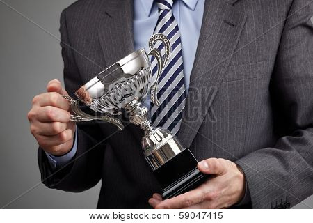 Businessman celebrating with trophy award for success in business or first place sporting championship win