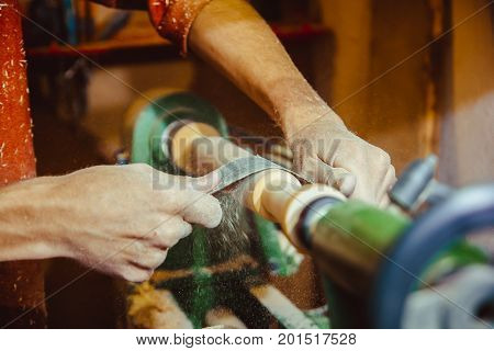 Wood turners using sandpaper polished wood on a lathe