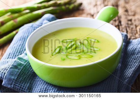 Cream Of Green Asparagus Soup In Bowl, Garnished With Sliced Asparagus On Top, Fresh Asparagus In Th