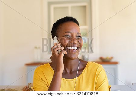 Smiling african american woman talking on the phone. Mature black woman in conversation using mobile phone while laughing. Young cheerful lady having fun during a funny conversation call.