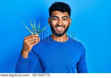 Arab man with beard holding picklock to unlock security door looking positive and happy standing and smiling with a confident smile showing teeth 