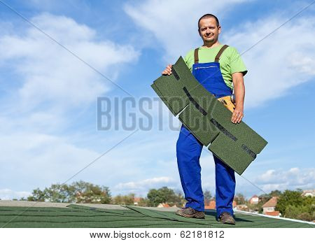 Worker Putting Bitumen Shingles On A Roof