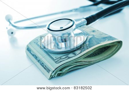 a stethoscope on a wad of US dollar bills, depicting the concepts of the health care industry or the health care costs