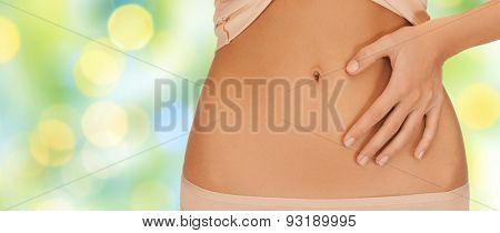 health, digestion, beauty, people and weigh loss concept - close up of woman pointing finger to belly over green lights background