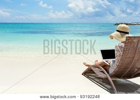 Business woman using laptop computer on the beach