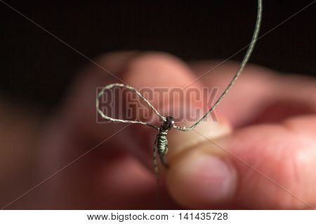 Man hand tying a fishing hook. Tie the rig.  Selective focus. Tie Hook Close Up. Tie Fishing Hook  Tying a fishing hook Process. Tie the KD rig and catch more carp.