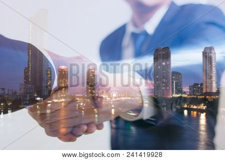 Double Exposure Concept. Investor Business Handshake With City Night. Businessman Shaking Hands Usin