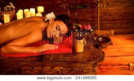 Massage of woman in spa salon. Girl on candles background in massage spa salon. Luxary interior in oriental therapy salon. Female have relax after sport. Spa salon is corner of silence and tranquility