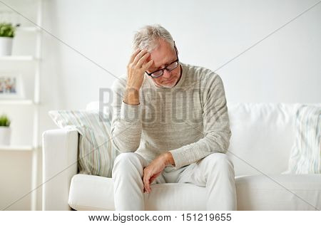 health, pain, stress, old age and people concept - senior man suffering from headache at home