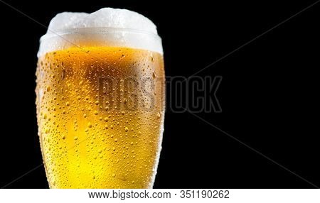 Beer. Cold Craft light Beer in a glass with water drops. Pint of Beer close up isolated on black color background. Ale beer Border design. Closeup