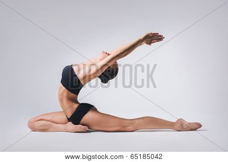 young beautiful yoga posing on a gray studio background